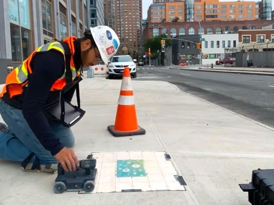 A man wearing a helmet is playing with a toy car on a tiled floor