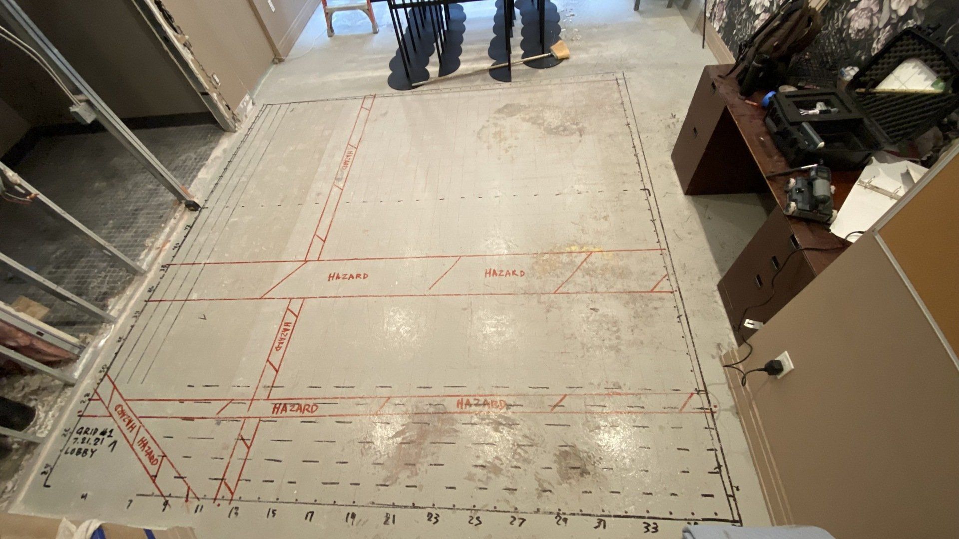 A couple of men standing on a concrete floor with measurements on it.