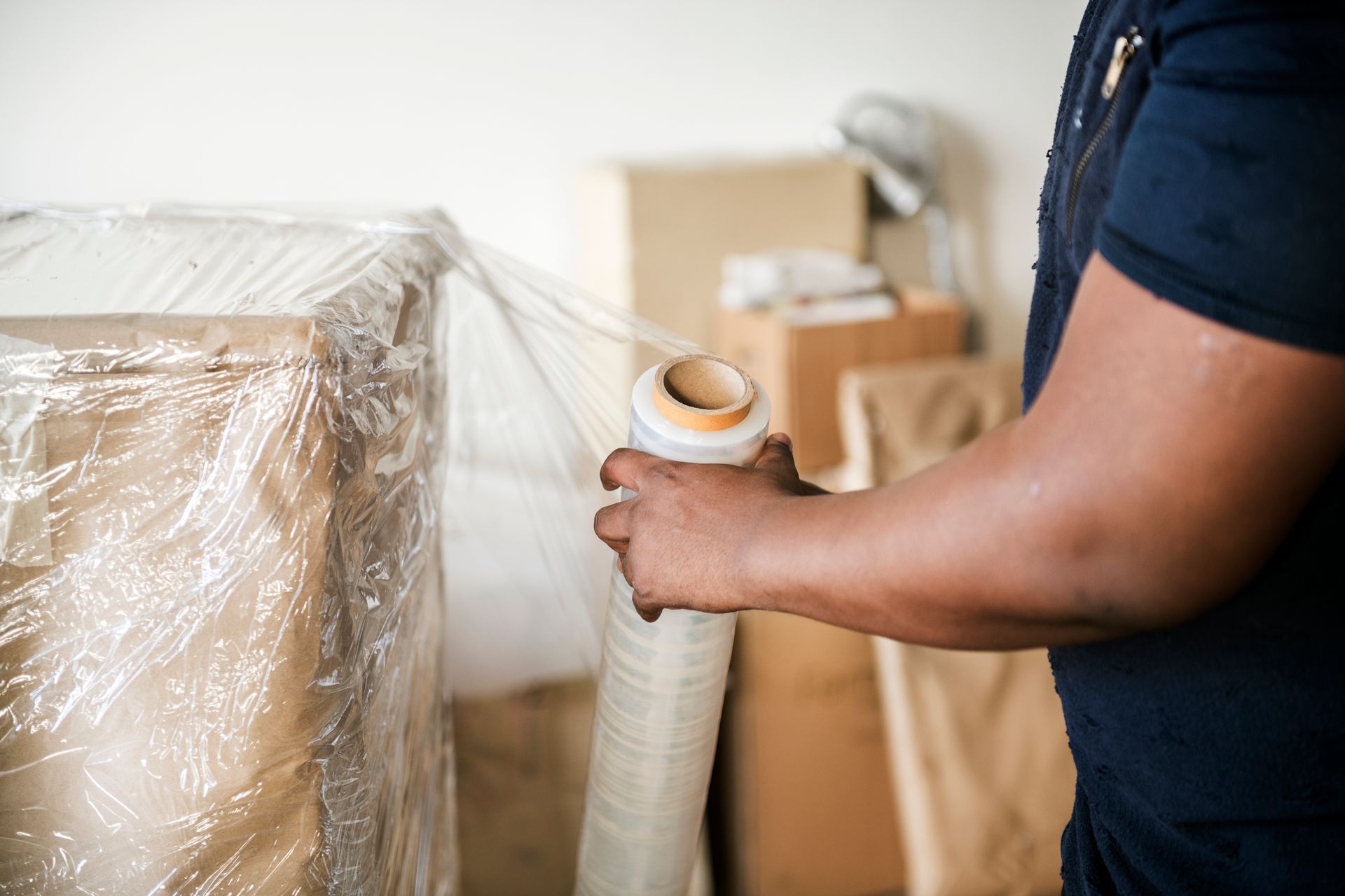 Person wrapping furniture in clear plastic during a move or storage prep