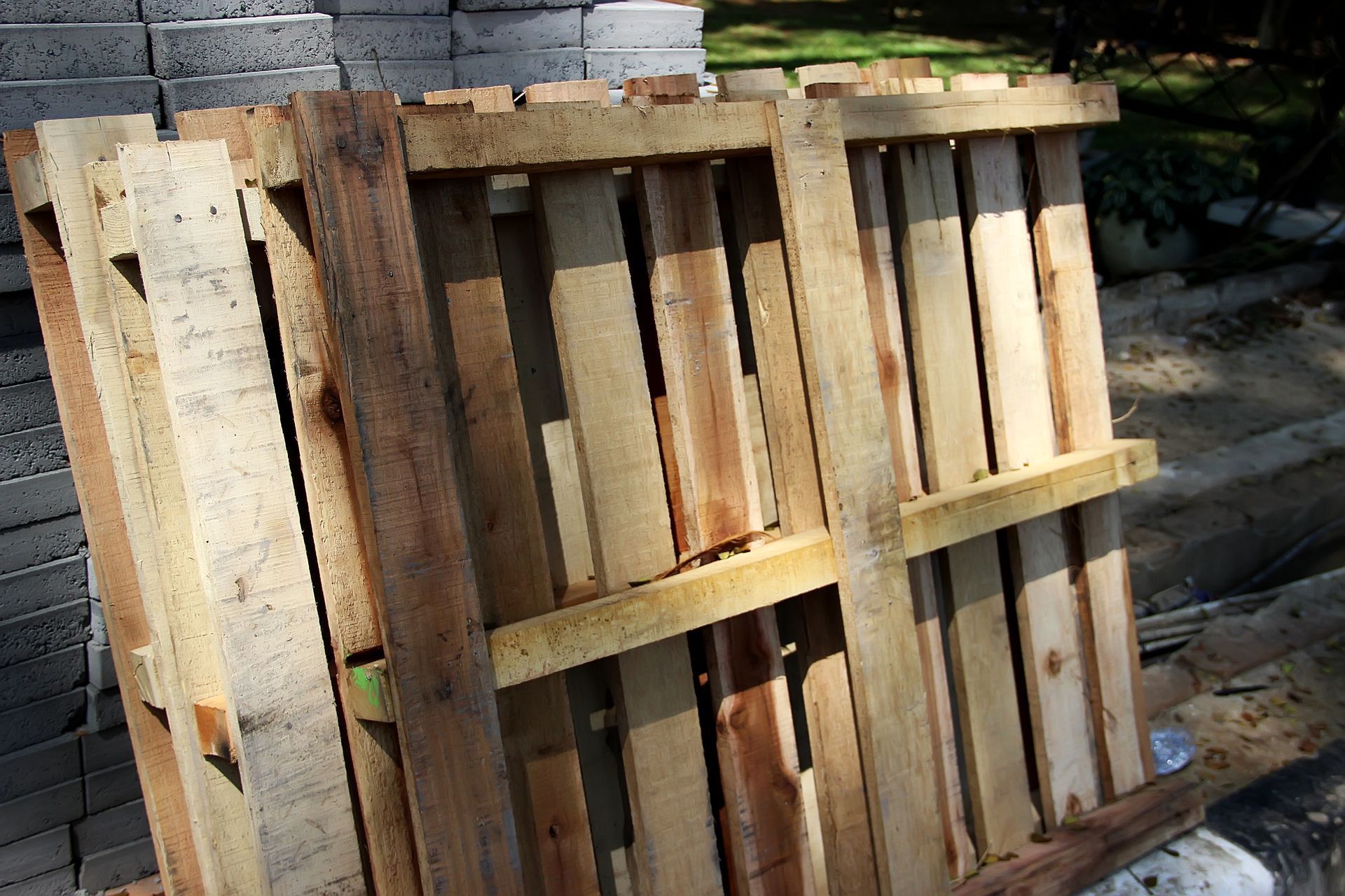Wooden pallet crate stacked outdoors beside concrete blocks and trees