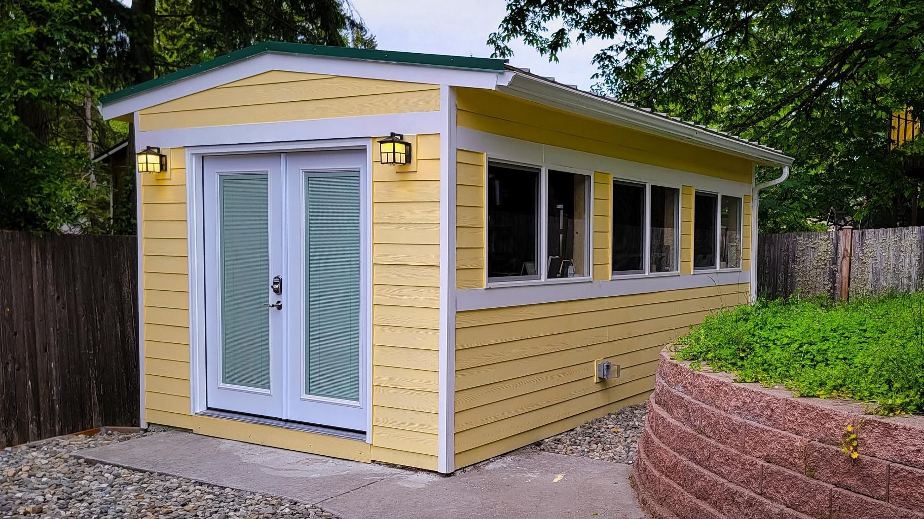 A yellow and white shed with a green roof.