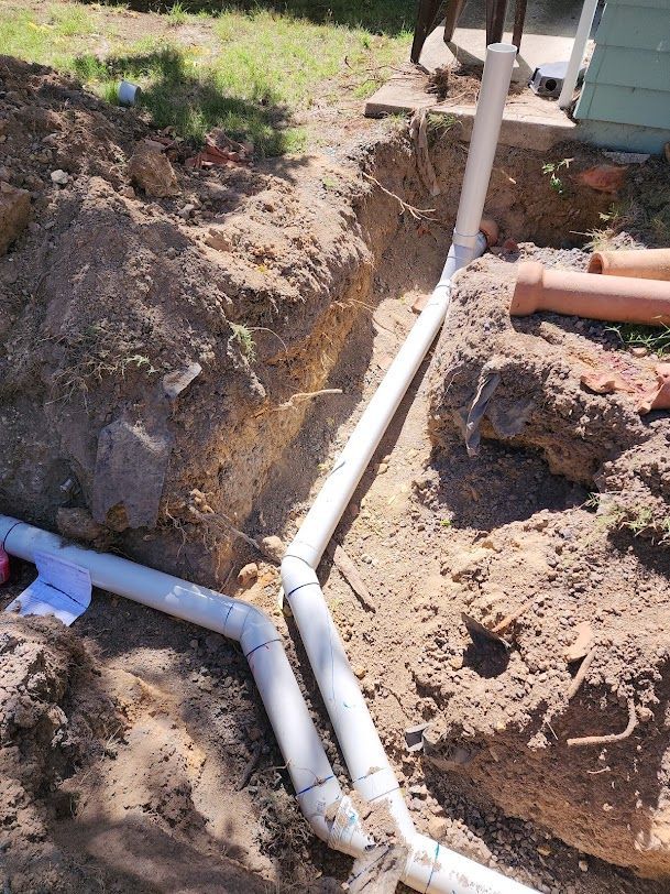 A Bunch Of White Pipes Are Laying In The Dirt — RAW Plumbing & Gasfitting In Pearce, ACT