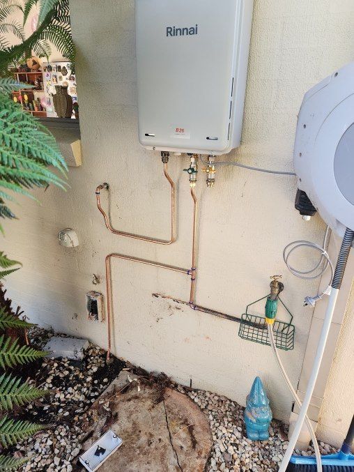 A White Water Heater Is Mounted To A Wall — RAW Plumbing & Gasfitting In Pearce, ACT