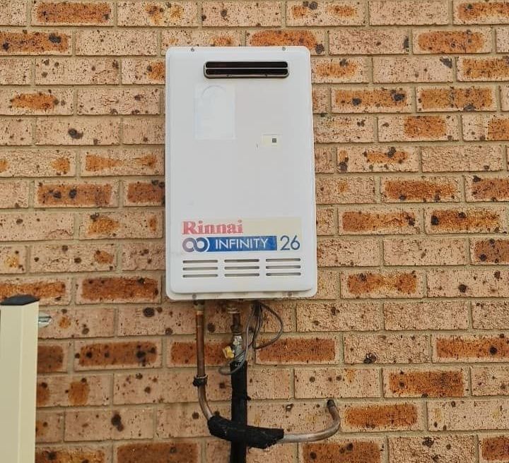 A Rinnai Water Heater Is Mounted To A Brick Wall — RAW Plumbing & Gasfitting In Pearce, ACT