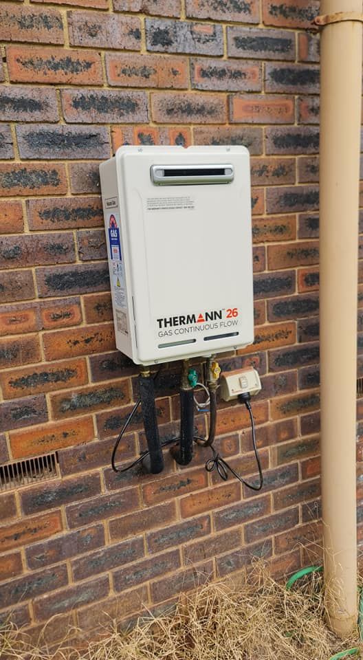 A White Water Heater Is Mounted On A Brick Wall —  RAW Plumbing & Gasfitting In Pearce, ACT