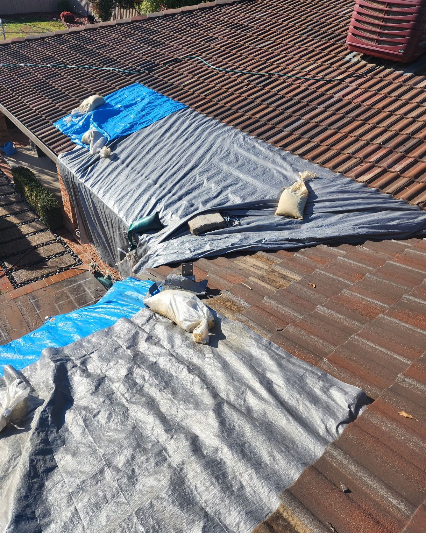 A Roof Is Covered In Tarps And Bags Of Sand — RAW Plumbing & Gasfitting In Pearce, ACT