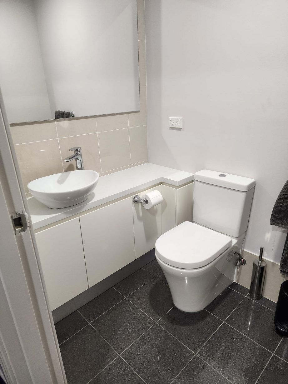 A Bathroom With A Toilet , Sink And Mirror — RAW Plumbing & Gasfitting In Pearce, ACT