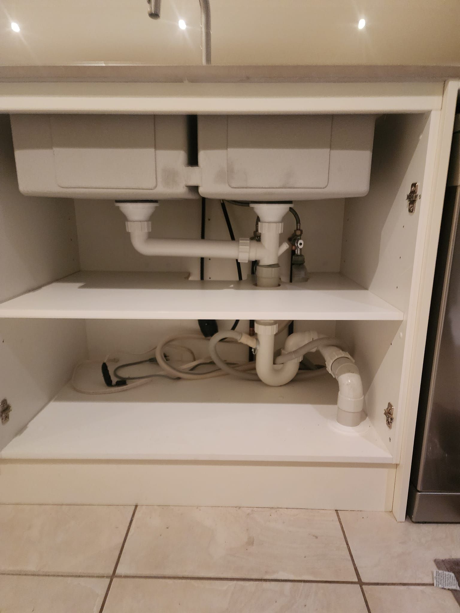 A Kitchen Sink Is Sitting Under A Cabinet With Pipes Coming Out Of It — RAW Plumbing & Gasfitting In Pearce, ACT