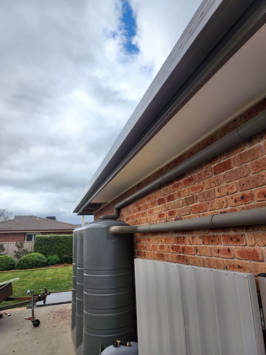 A Brick House With Two Water Tanks On The Side Of It — RAW Plumbing & Gasfitting In Pearce, ACT