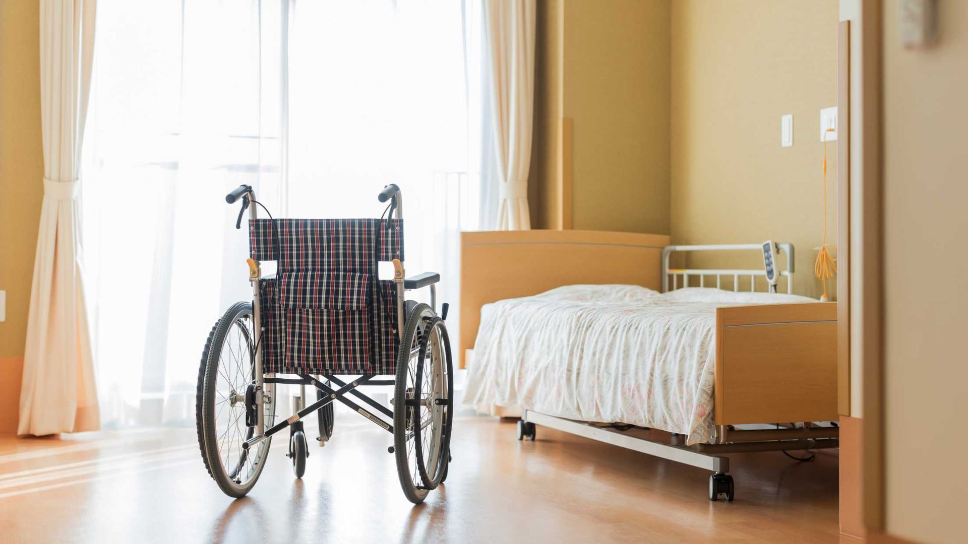 A wheelchair is parked next to a bed in a hospital room.