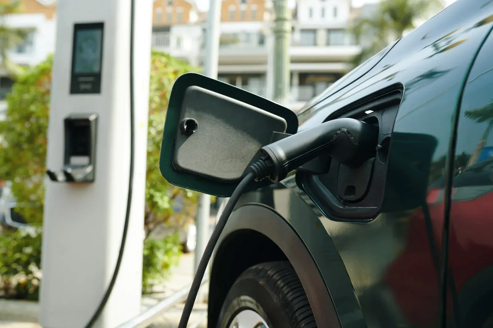 Electric car charging at a station, with a plug connected to the vehicle’s side port.