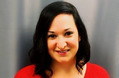 A woman in a red sweater is smiling for the camera.