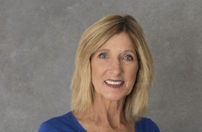 A woman in a blue shirt is smiling for the camera.
