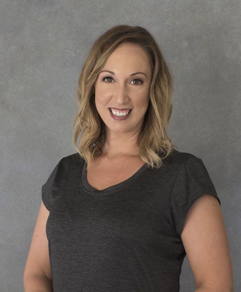 a woman in a grey shirt is smiling for the camera .