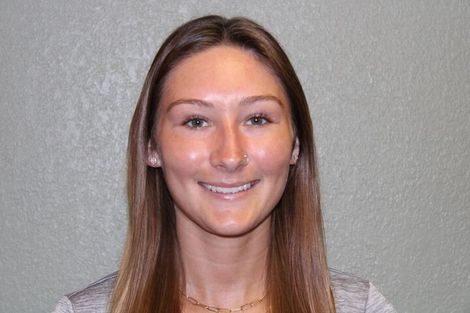A woman with long brown hair is smiling for the camera.