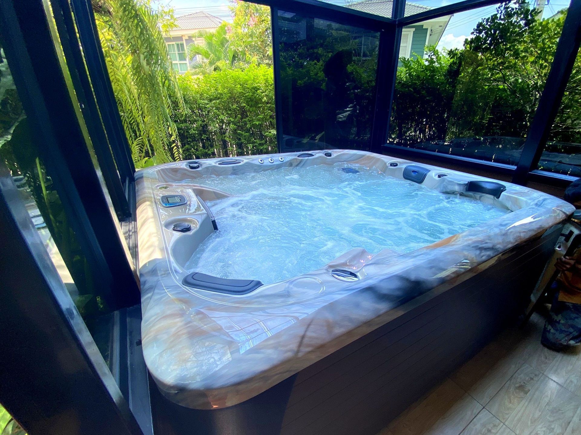 Q&G RAIN FOREST hot tub inside a glass-walled room surrounded by lush garden greenery in Khlong Sam Wa, Bangkok