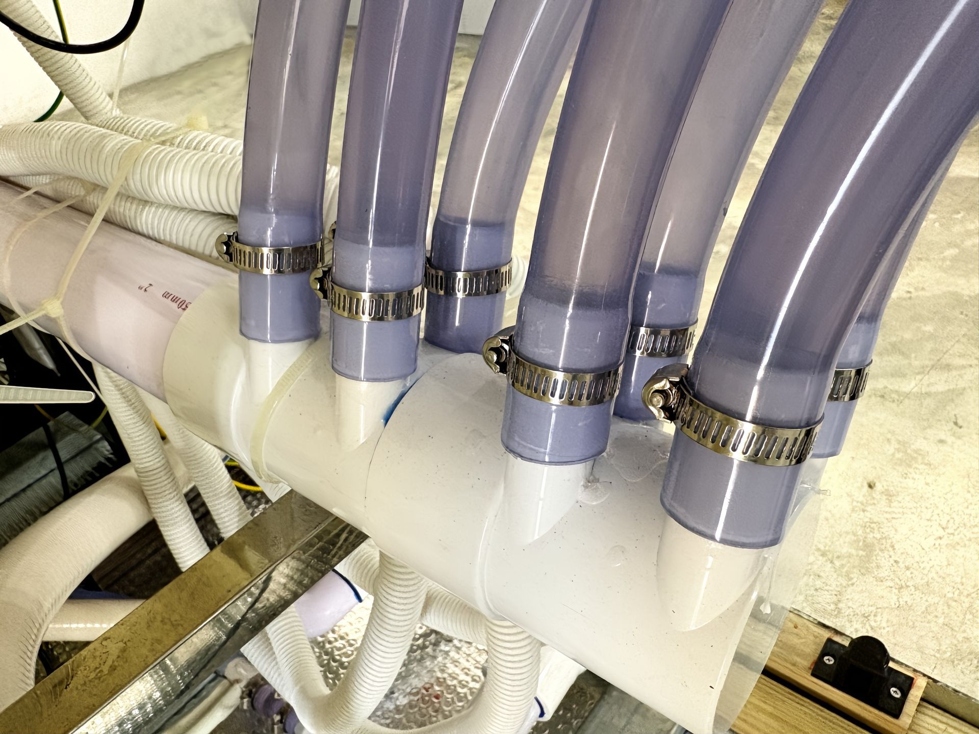 Swim spa plumbing system featuring multiple reinforced water lines connected to a central manifold with secure clamps, designed to reduce leakage and ensure reliable water circulation.