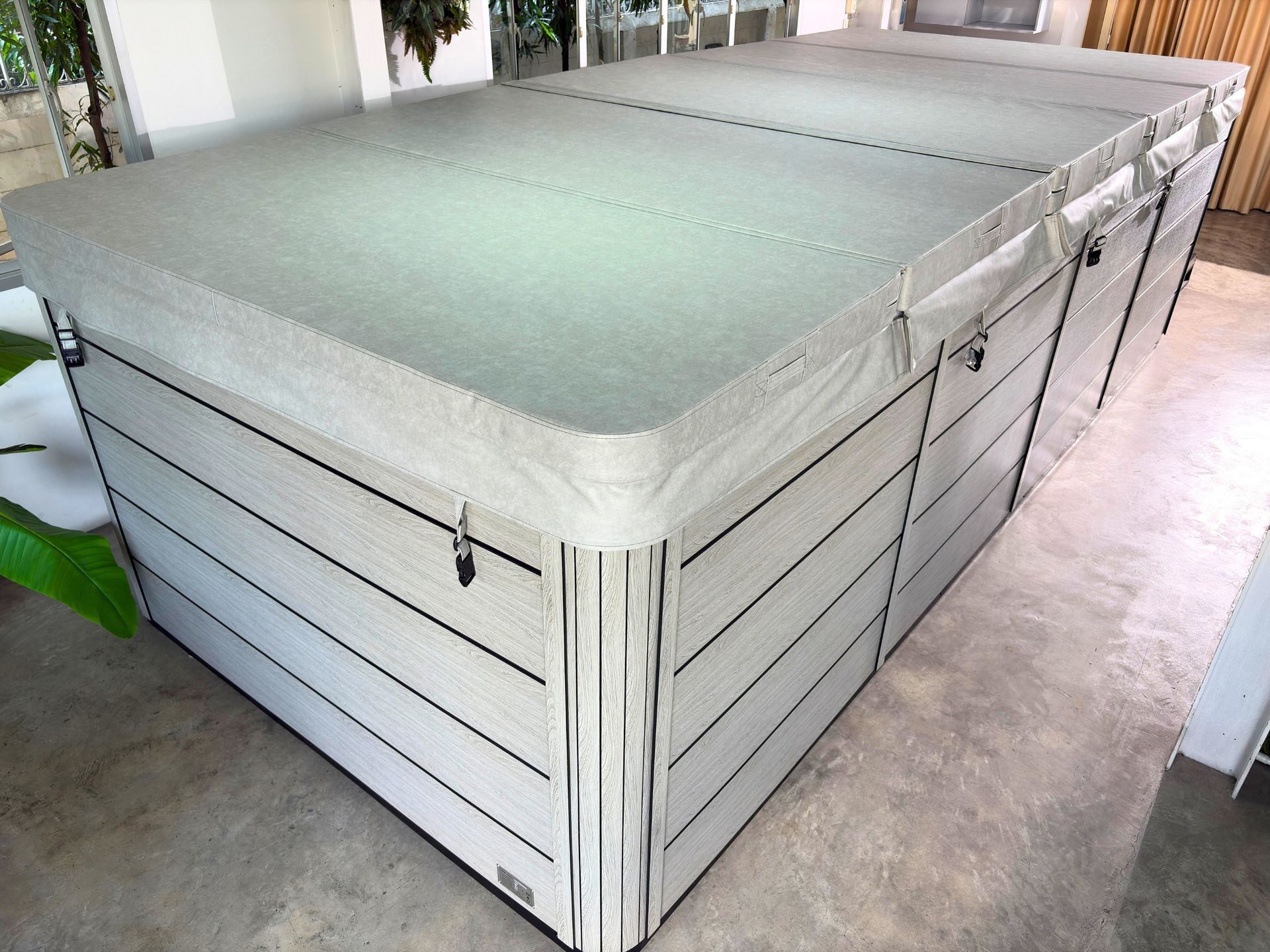 outdoor swim spa with full insulated hard cover closed, featuring durable gray cabinet panels and secure locking straps for heat retention and protection.