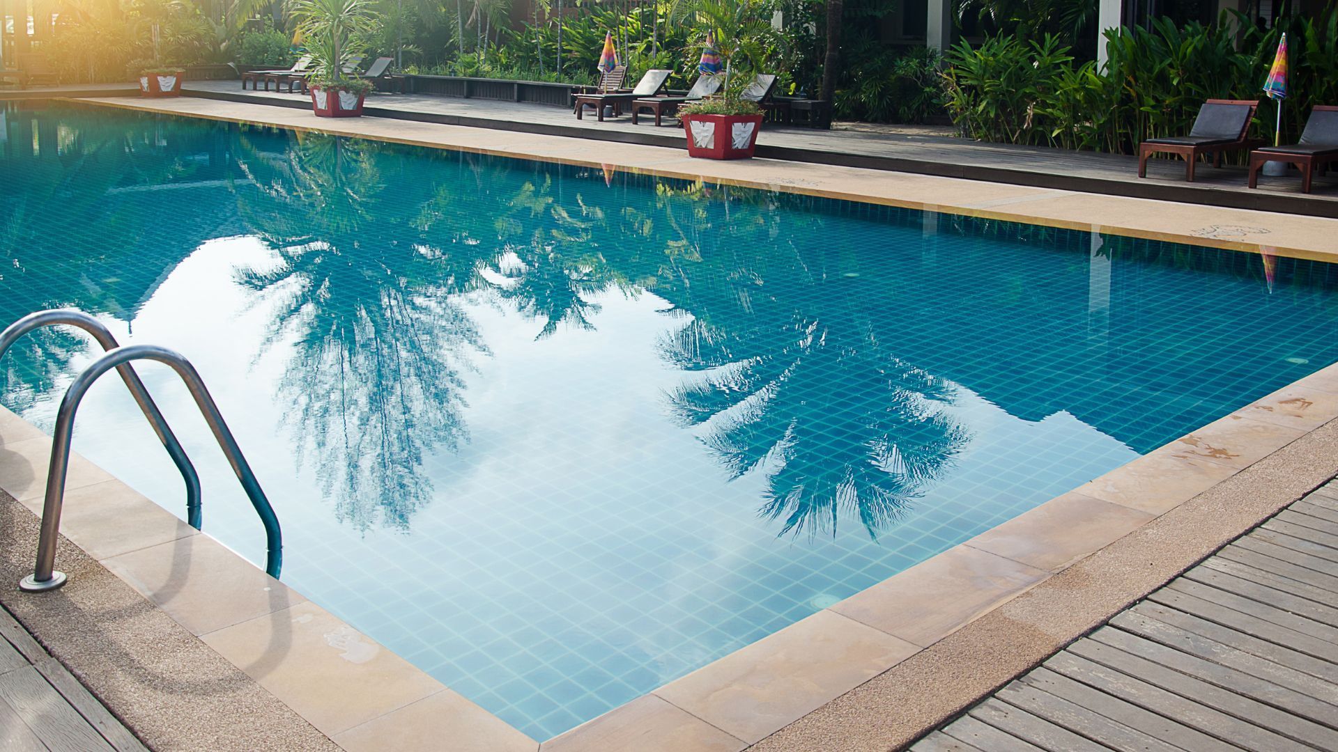 Traditional rectangular swimming pool with clear blue water, surrounded by tiled deck and landscaped outdoor area for residential leisure and relaxation.