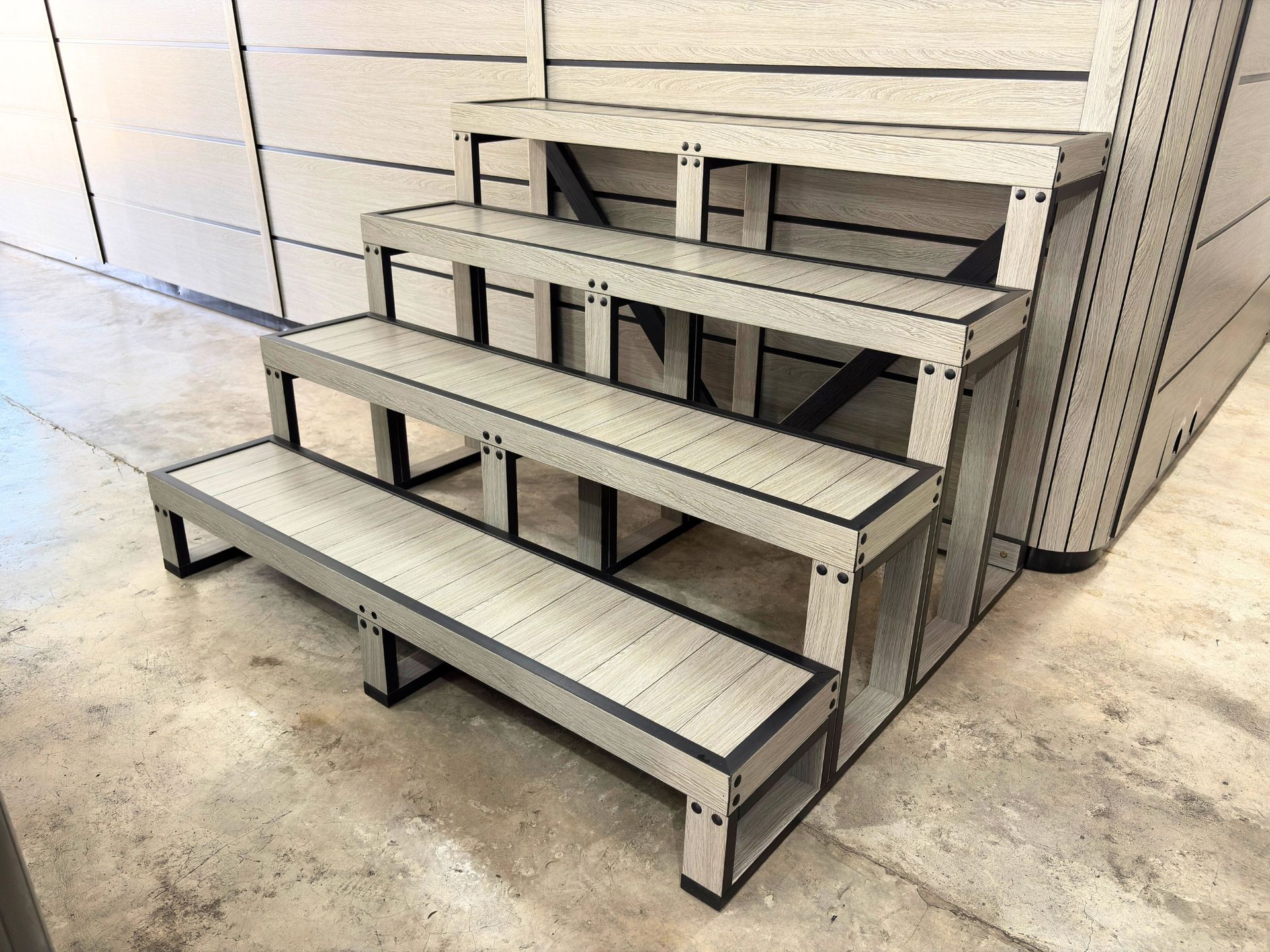 Four-tier swim spa Athens series steps made of composite material positioned against a matching spa cabinet.