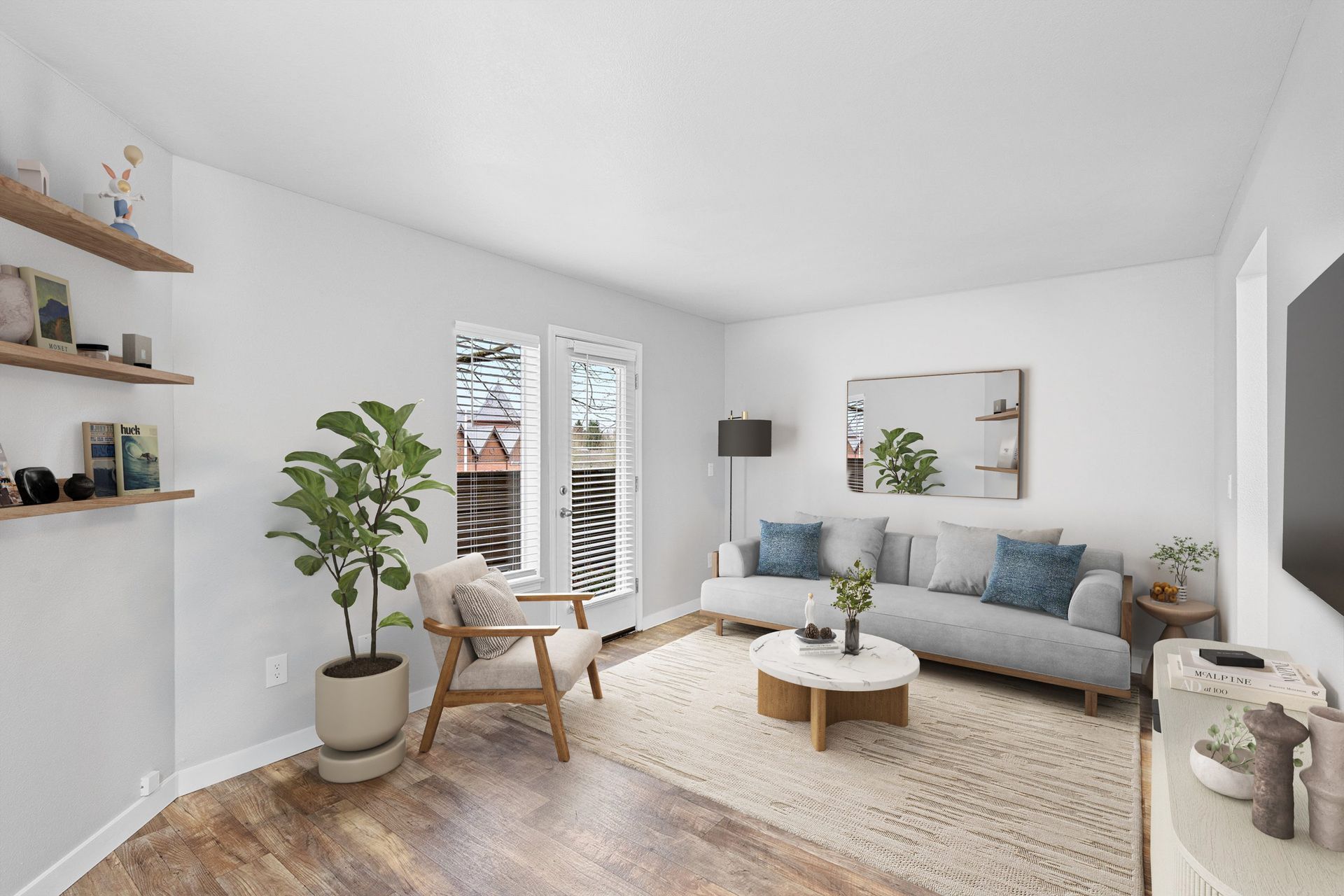 Bright living room in a modern apartment with a gray sofa, wooden floor, and plants.