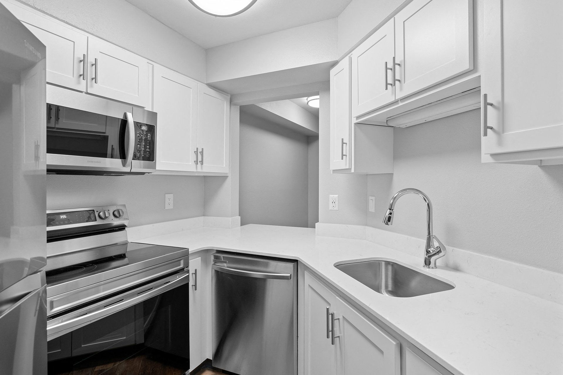 Modern white kitchen with stainless steel appliances and a sink.