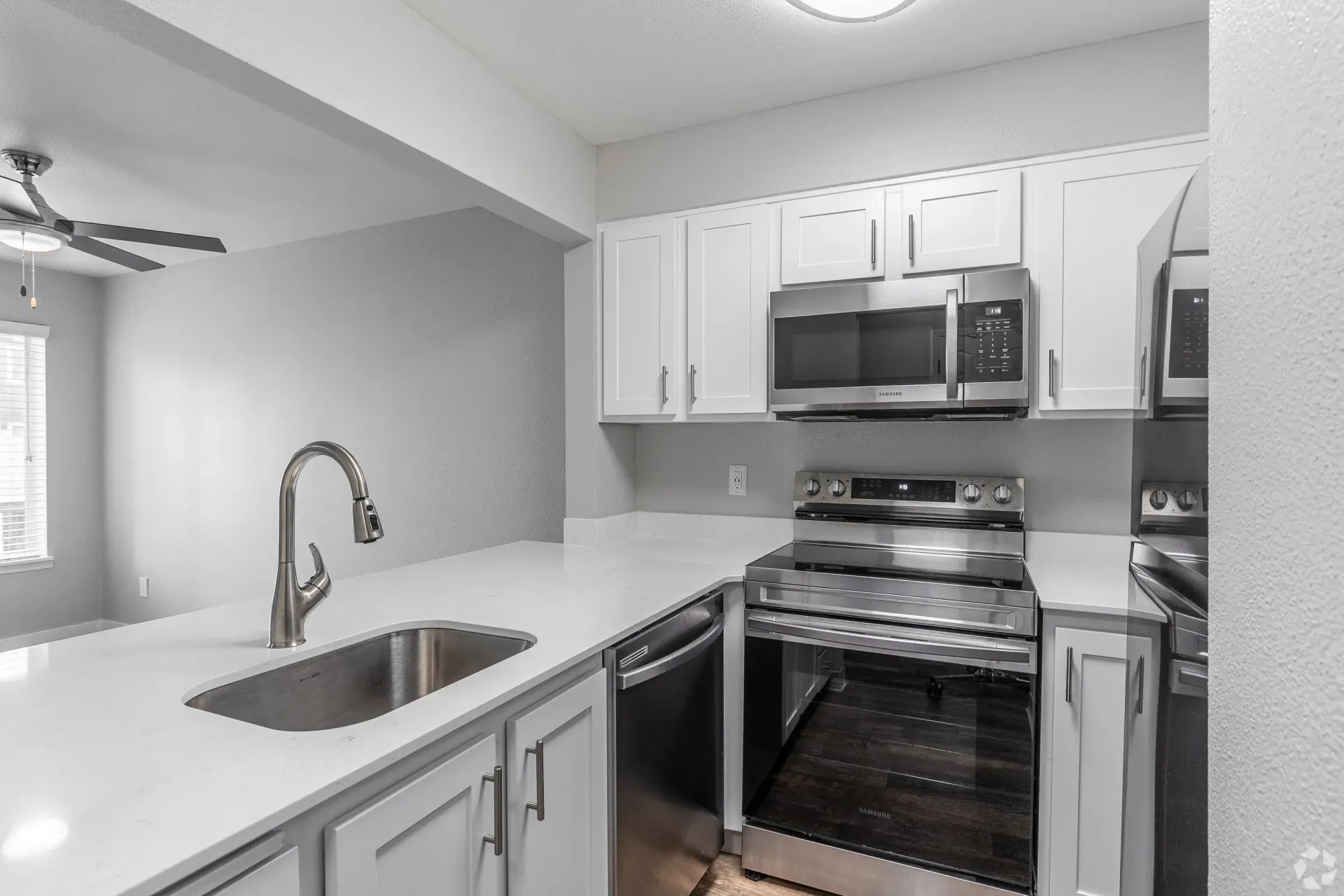 Modern kitchen with white cabinets, stainless steel range and microwave, and a curved faucet.