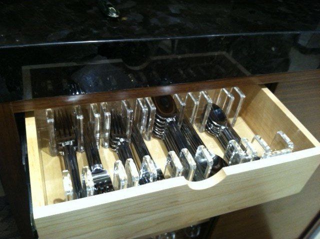 A wooden drawer filled with silverware including forks and spoons