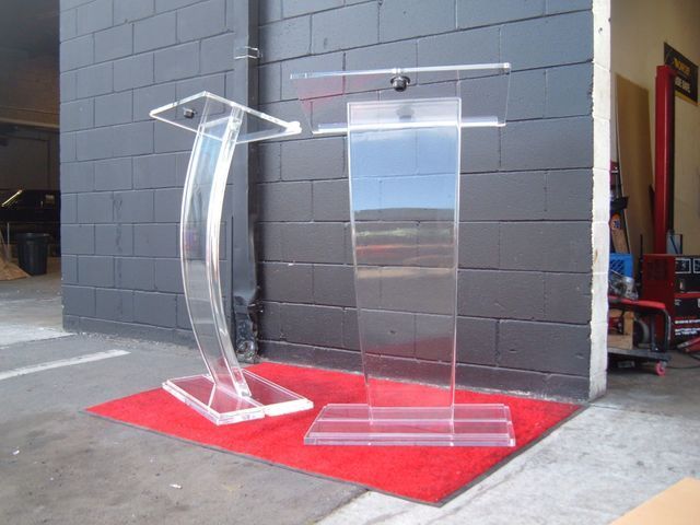 Two clear acrylic podiums are sitting on a red rug in front of a brick wall