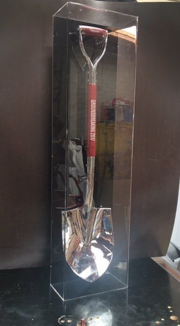 A shovel is displayed in a clear acrylic box.