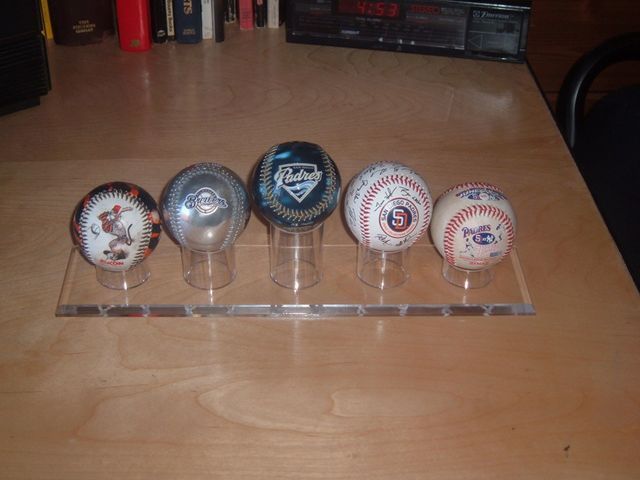 A row of baseballs on a table with one that says ' dodgers ' on it