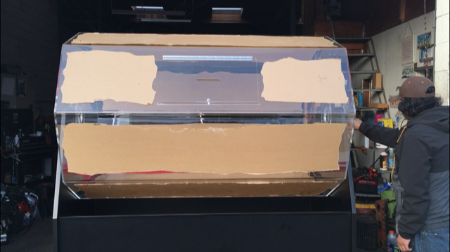 A man is standing in front of a large acrylic box.