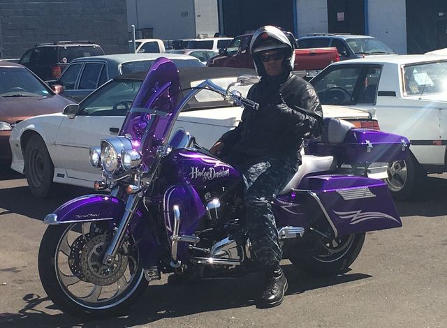 A man is riding a purple harley davidson motorcycle