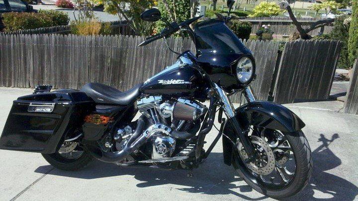 A black harley davidson motorcycle is parked on the sidewalk