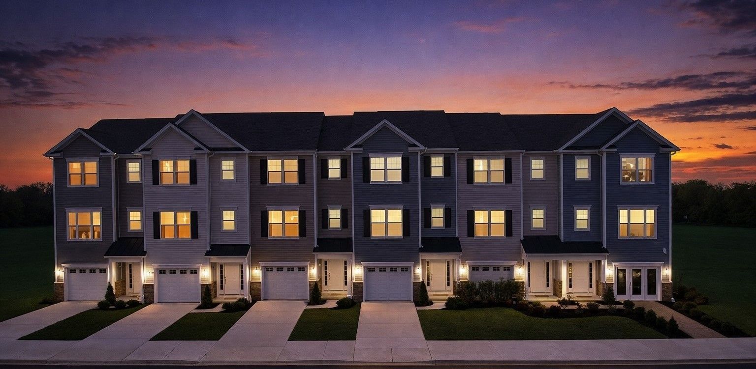 Row of modern beige townhouses with garages and lawns along a quiet street