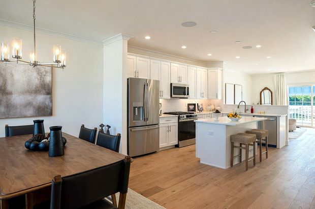 Modern kitchen and dining area with white cabinets, stainless appliances, and a dark wood table