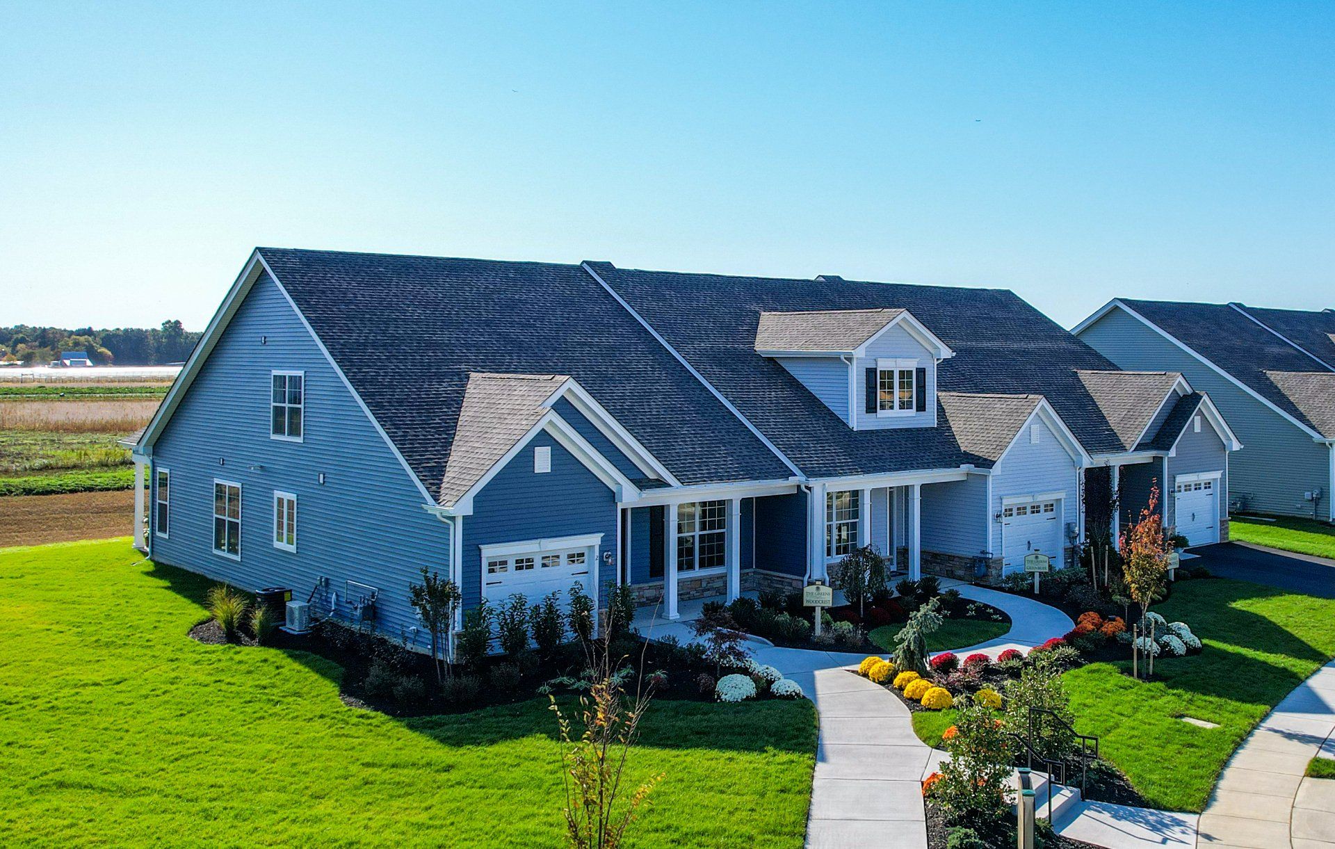Suburban blue house with a manicured lawn and curved walkway under a clear sky