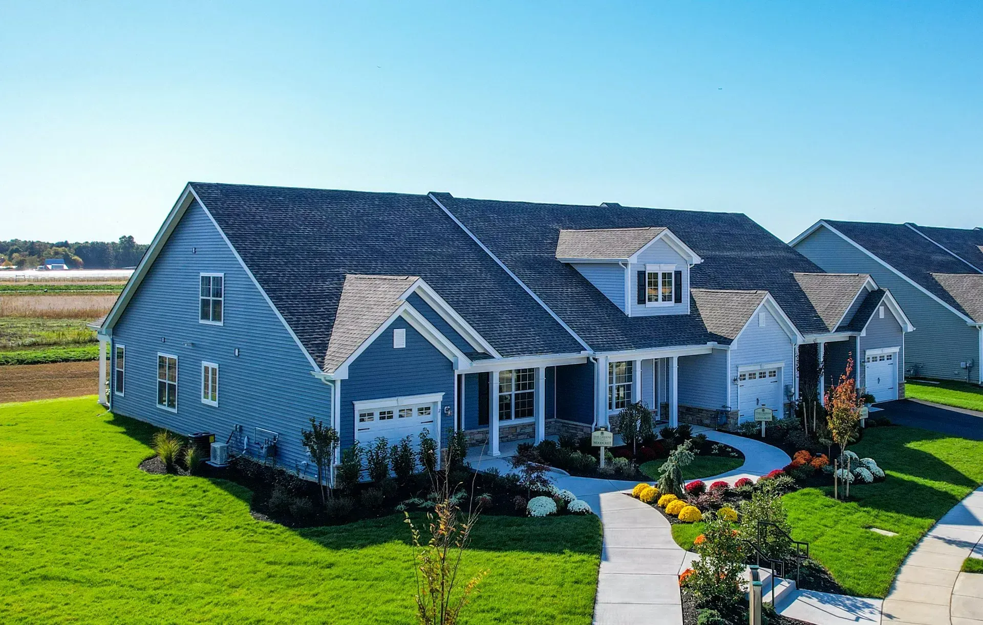 Blue suburban house with a manicured lawn, curved walkway, and bright blue sky