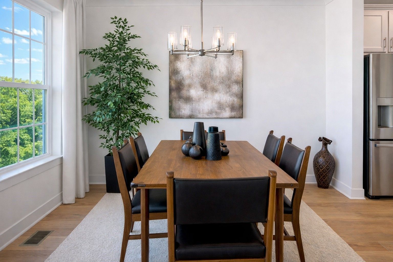 Modern dining room with wooden table, black chairs, large window, and wall art in bright natural light