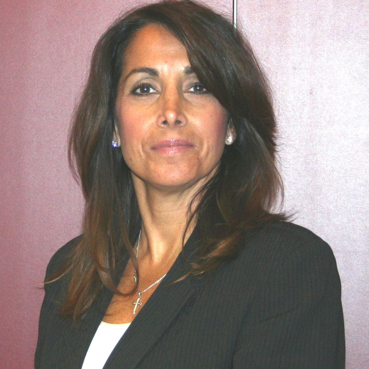 Portrait of a woman in a dark blazer against a pink background