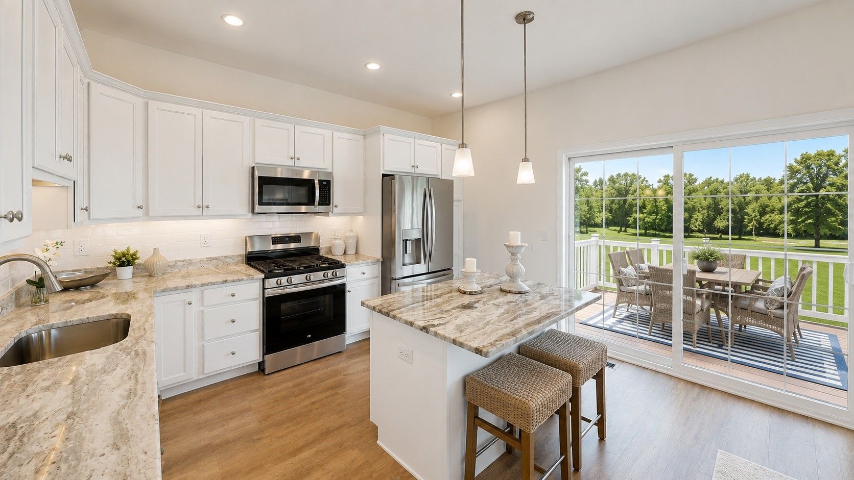 Bright modern kitchen with white cabinets, granite island, stainless appliances, and patio doors to a deck.