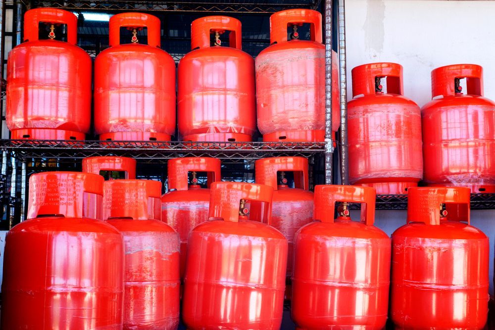 Stacks of Red Gas Cylinders Arranged on Metal Racks in a Storage Area — Kuranda Gas & Supplies In Mossman, QLD