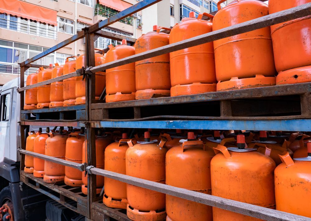Rows of Orange Gas Cylinders Stored on Metal Shelves in a Warehouse — Kuranda Gas & Supplies In Cow Bay, QLD