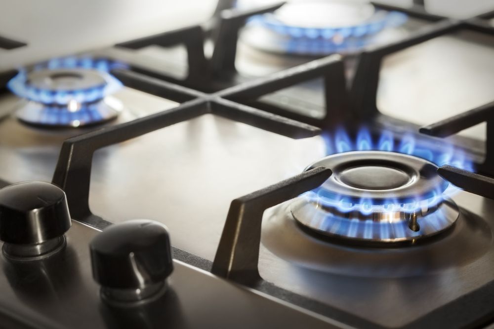 Close-Up of A Stainless Steel Gas Stovetop with Three Blue Flames Burning — Kuranda Gas & Supplies In Koah, QLD