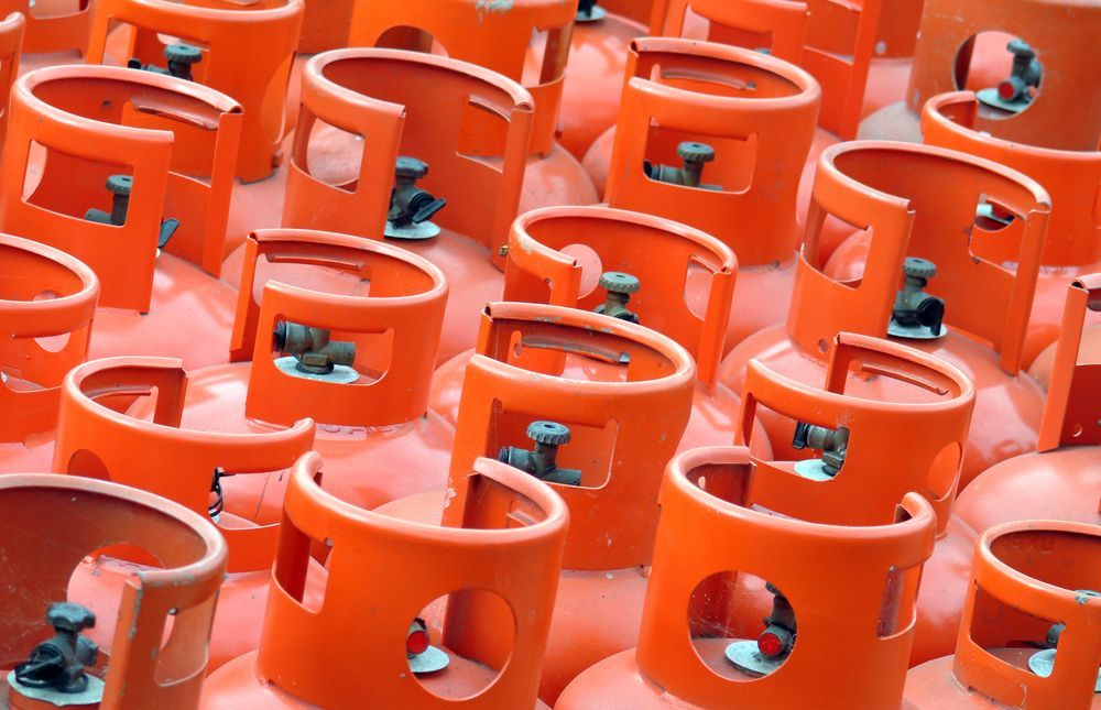 Rows of Orange Gas Cylinders with Blue Valves Stacked Closely Together — Kuranda Gas & Supplies In Cape Tribulation, QLD