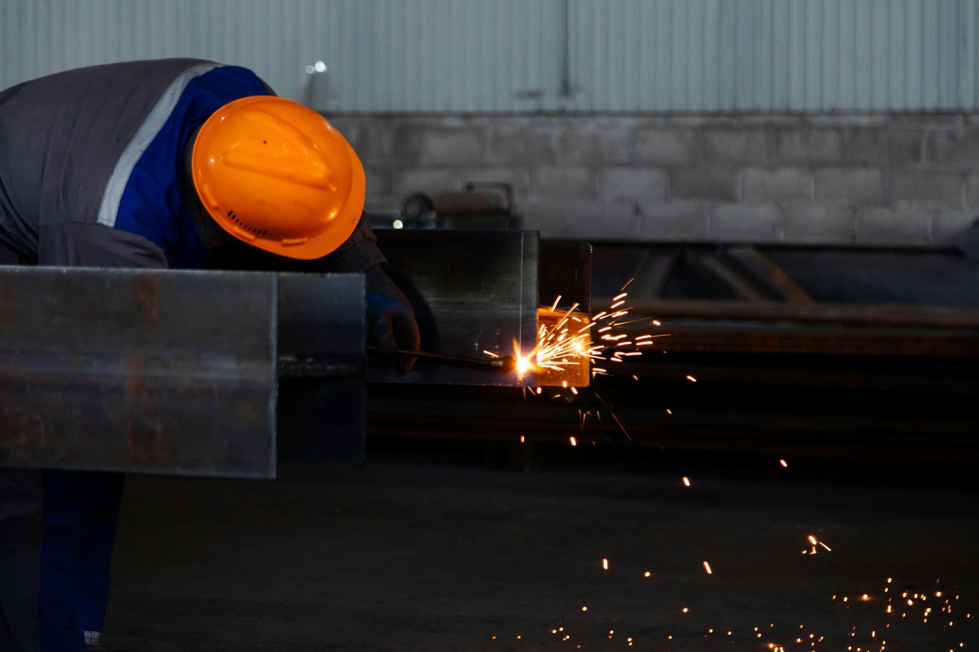 Person in Orange Hard Hat Welding Metal, Sparks Flying in An Industrial Setting — Kuranda Gas & Supplies In Koah, QLD