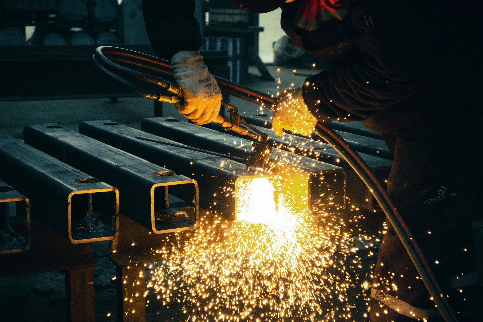 Worker Using a Torch to Cut Through Metal, with Sparks Flying in A Workshop — Kuranda Gas & Supplies In Koah, QLD