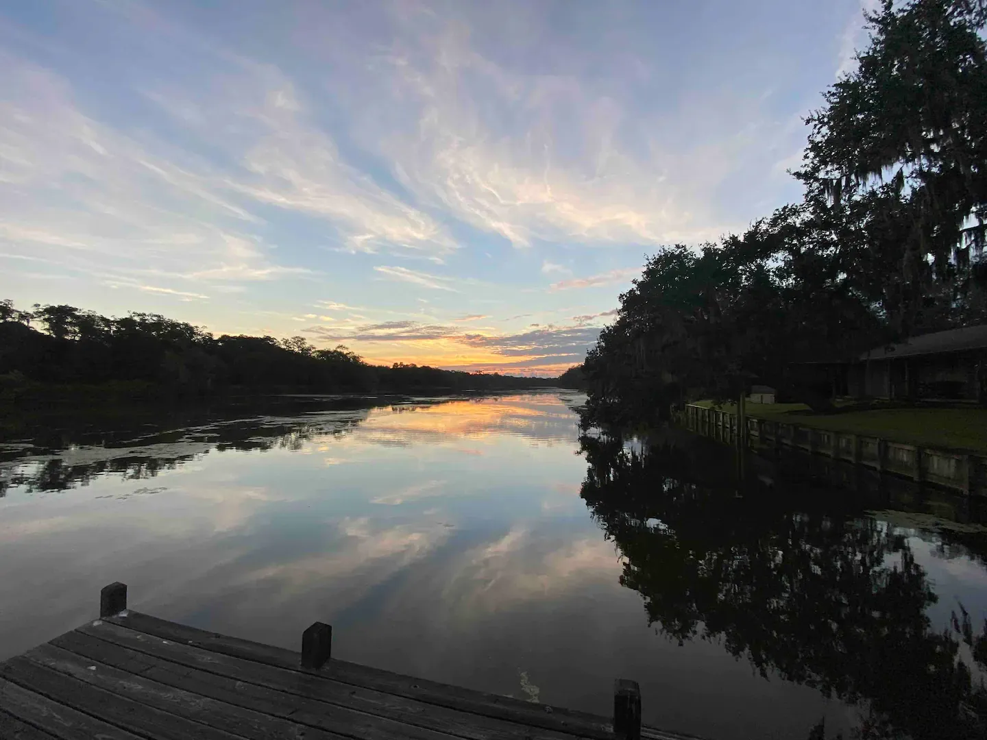 A sunset over a lake with a dock in the foreground