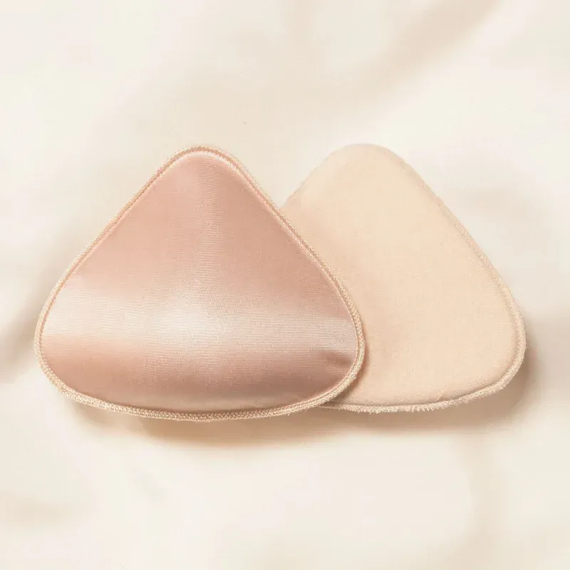 a pair of triangle shaped breast pads are sitting on top of a white cloth .