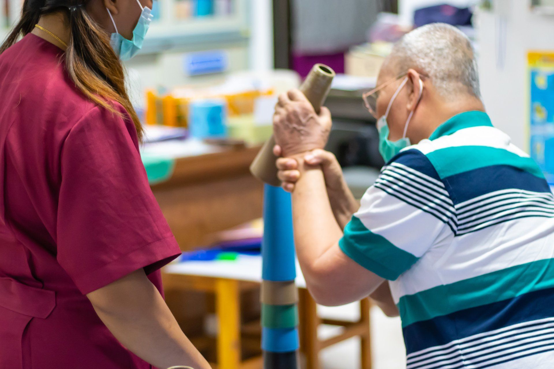 An elderly man is being helped by a nurse while wearing a mask.